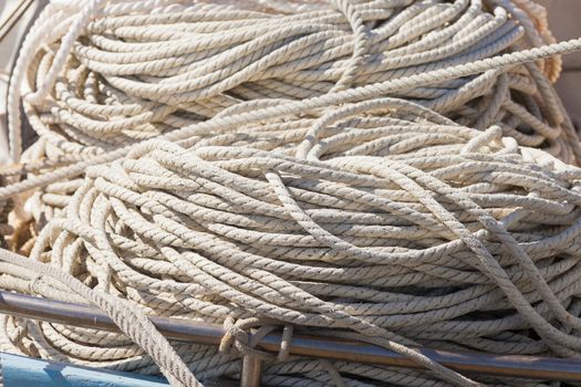 Pile of old worn hemp rope coils on boat deck background texture pattern.