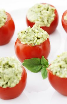 Stuffed Tomatoes filled with a pesto and avocado mixture. Extreme shallow depth of field with selective focus on center tomato.