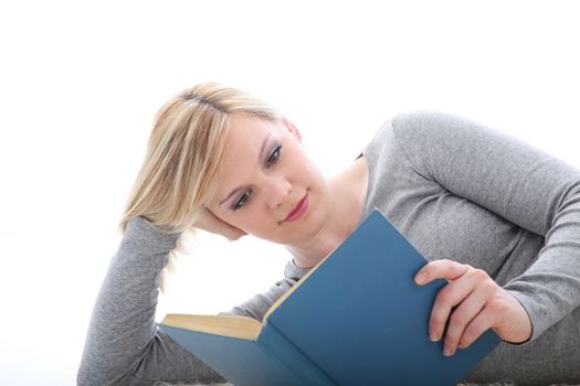 Young female student resting on her elbow on the floor reading a novel or studying for her classes 