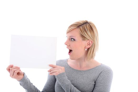 Woman with her mouth open in surprise looking at a blank sign that she is holding up to her side 