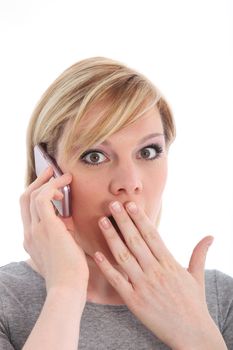 Young woman reacting in shock and horror to news she has just received over her mobile phone 