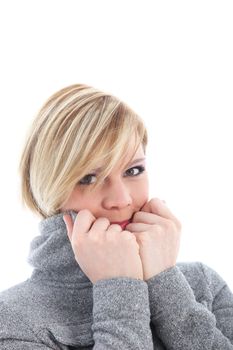 Woman shivering in the winter cold and pulling the collar of her jacket up close to her face in an effort to keep warm 