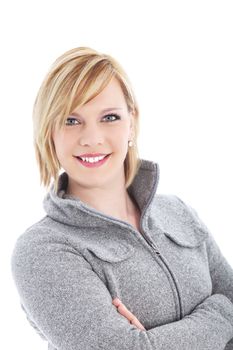 Attractive confident blonde woman with a lovely friendly smile standing in a warm winter top with her arms crossed 