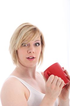 Startled woman with wide open eyes holding a large red mug of coffee isolated on white