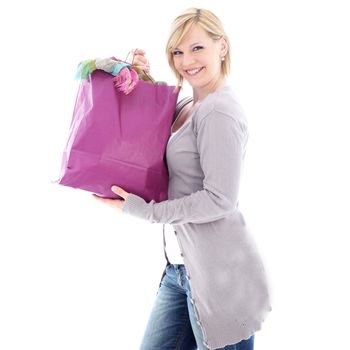 Happy woman smiling in glee after a successful shopping spree as she carries home a carrier bag crammed full of new clothing 