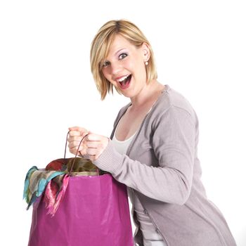 Ecstatic shopaholic with a carrier bag full of purchases laughing in anticipation of her new clothing 
