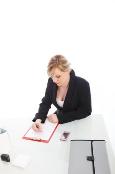 High angle view of a young businesswoman working at her desk completing a questionnaire attached to a clipboard High angle view ofa young businesswoman working at her desk completing a questionnaire attached to a clipboard 