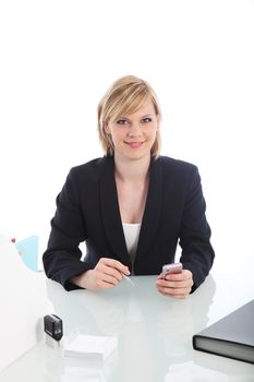 Young stylish business executive sitting at her desk holding her phone in one hand and a pen in the other in a white office environment Young stylish business executive sitting at her desk holding her phone in one hand and a pen in the other 