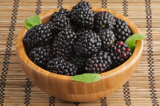 Perfect Ripe Blackberries in Wooden Bowl isolated on Strawmat background