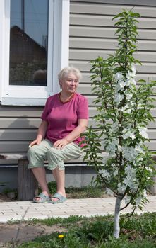 Woman on a summer residence admires blossoming garden