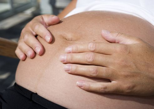 Pregnant woman holding her hands on the stomach