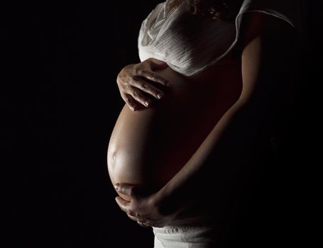 Pregnant woman holding her hands on the stomach