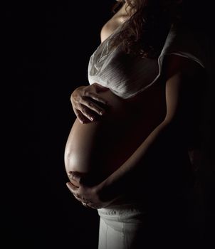 Pregnant woman holding her hands on the stomach