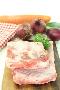 Beef spare ribs with parsley and carrot on a wooden board