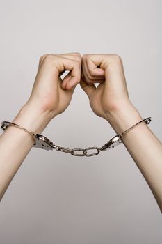 Unreconizable teenager with handcuffs on grey background
