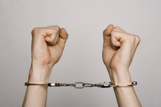 Unreconizable teenager with handcuffs on grey background