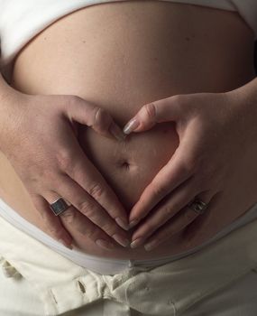 Heartshaped hands on a pregnant stomach
