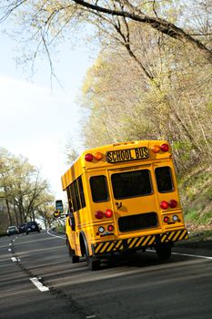 A short yellow school bus driving on the highway.