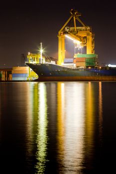 Industrial Container Cargo freight ship with working crane bridge in shipyard at dusk for Logistic Import Export background