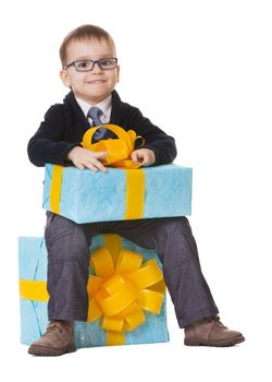 Small happy boy in spectacles with big presents on white background