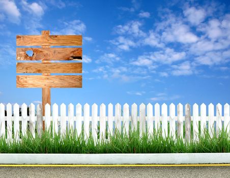 wooden signpost with white fence and blue sky