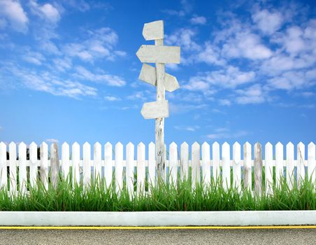 wooden signpost with white fence and blue sky