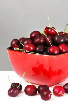 Red bowl of delicious fresh ripe and plum cherries, great nutrition background. 