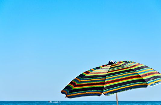 Colorful umbrella against the blue sky and the sea horizon