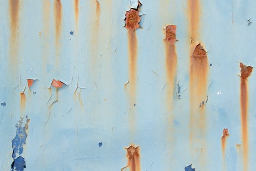 A metal plate with flaking blue paint in layers and patches of rust and orange streaks.