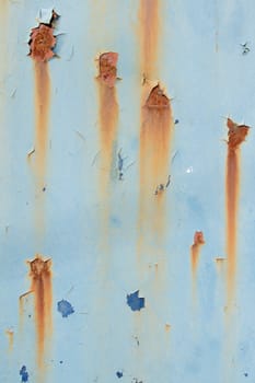 A metal plate with flaking blue paint in layers and patches of rust and orange streaks.