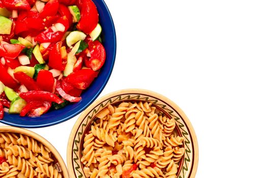 A bowl of salad and two plates with pasta with tomatoes, isolated on white background