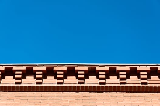 Decorative eaves from a red brick against the blue sky.