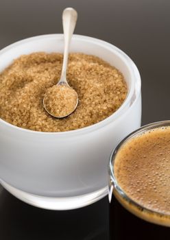 Black expresso coffee in small glass cup with sugar in white bowl reflecting
