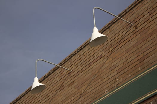 exterior store front lights with a brick wall and blue skies.