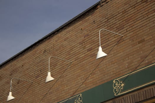 exterior store front lights with a brick wall and blue skies.