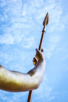 An image of a golden spear in front of a blue sky