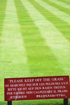 Multilingual keep off the grass sign