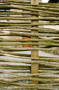 Background of fence made of weaven wooden branches and house yard.
