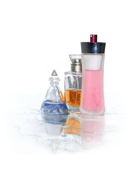 Three bottles of perfume standing on wet glass surface. Clipping path is included