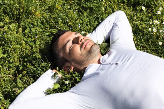 young man sleeping on the grass in a park