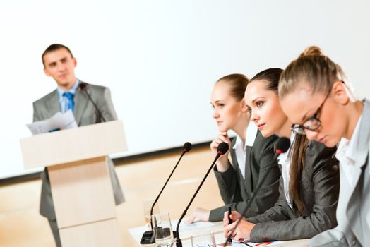 businessmen communicate at the conference, sitting at the table, on the table microphones and documents