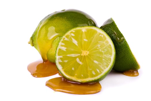 Close up view of a group of limes isolated on a white background with honey.