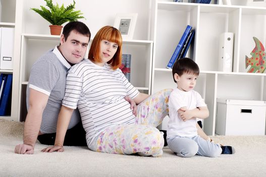 portrait of a pregnant woman, father and his son, at home