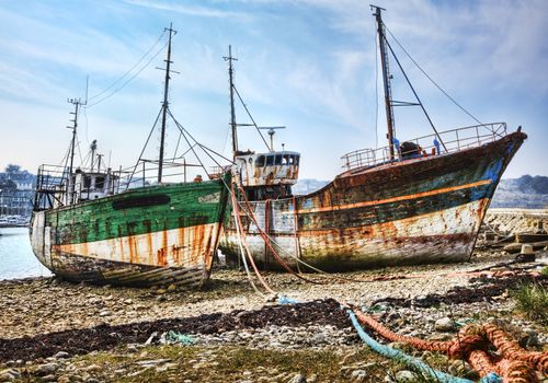 Wrecks of wooden ships anchored on an empty shore at the Atlantic Ocean.