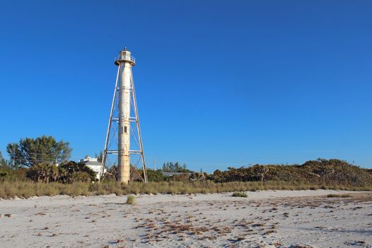The Gasparilla Island Rear Range Light on Gasparilla Island, Florida viewed from the beach with sea oats (Uniola paniculata) and other plants in the foreground and a clear blue sky