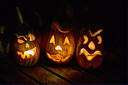 HDR image of carved eggplant jack o'lanterns on a small table in the dark for the halloween holiday