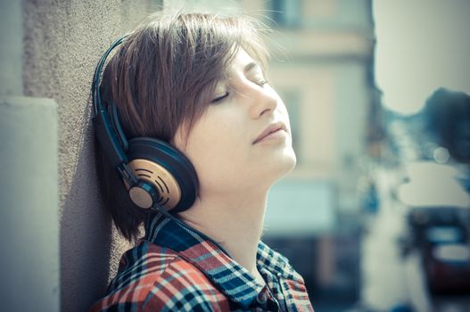 young hipster woman listening to music on balcony