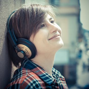 young hipster woman listening to music on balcony