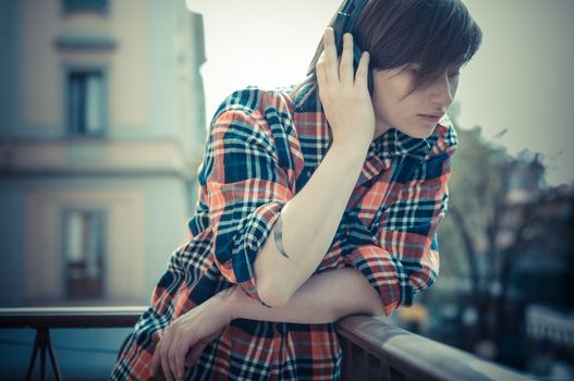 young hipster woman listening to music on balcony