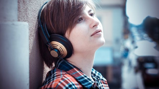 young hipster woman listening to music on balcony